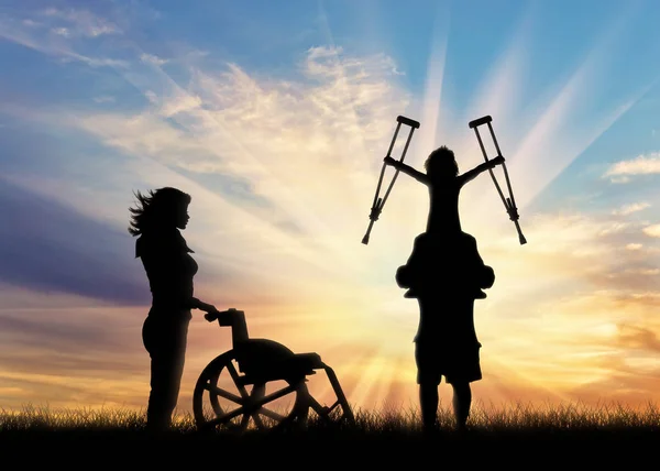 Gehandicapt kind op schouders van vader holding zijn krukken en een rolstoel verpleegkundige zonsondergang — Stockfoto