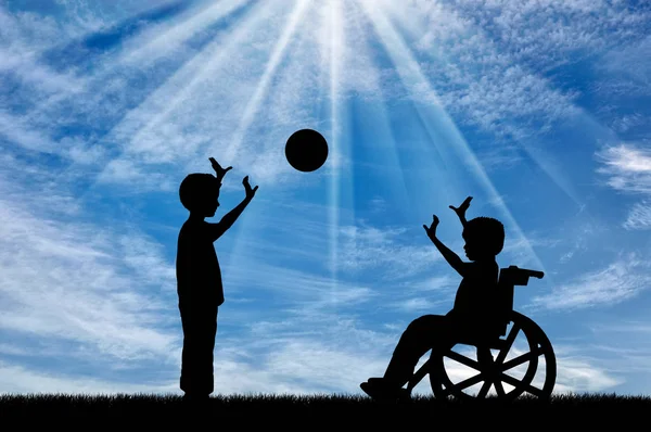 Pojke i rullstol spelar med pojke i bollen dag — Stockfoto