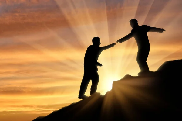 Wspinacz pomaga przyjaciel w górach dając pomocną dłoń zachód słońca — Zdjęcie stockowe