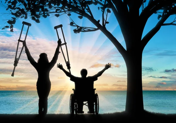 Feliz inválido com muletas e em cadeira de rodas perto do mar e da árvore — Fotografia de Stock