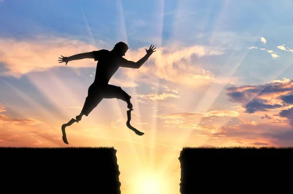 Disabled athlete with prosthetic leg jumping over precipice on sunset — Stock Photo, Image
