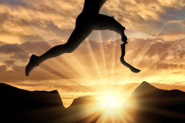 Atleta com deficiência com prótese perna saltando através da rocha no pôr do sol — Fotografia de Stock