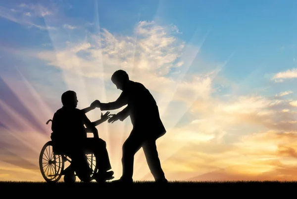 Personas con discapacidad en silla de ruedas obtener ayuda en la puesta del sol —  Fotos de Stock