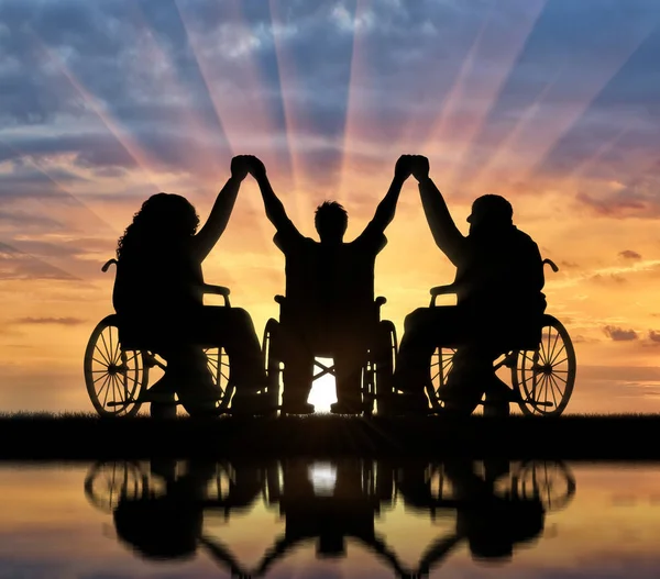 Инвалиды в инвалидных колясках держатся за руки закат и отражение — стоковое фото