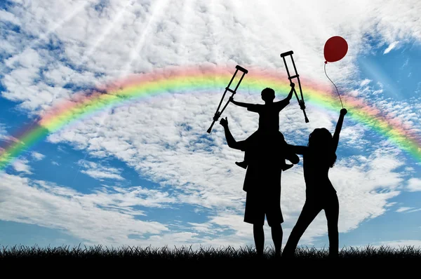 Child disabled person with crutches with his parents and rainbow