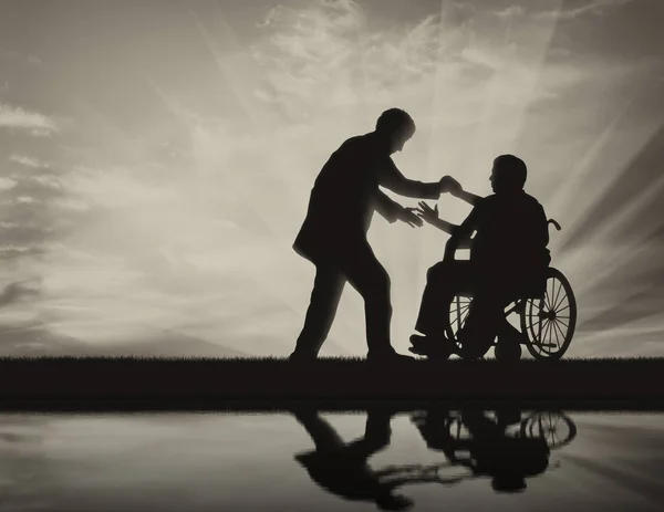 L'homme aide une personne en fauteuil roulant — Photo