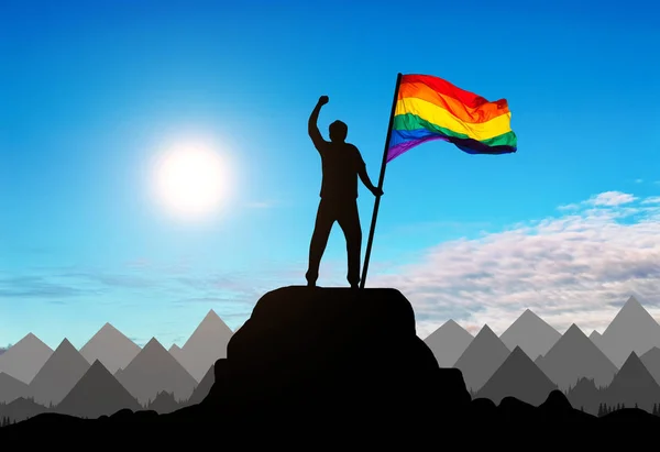 Sylwetka z gejem tęczowa flaga na szczycie góry — Zdjęcie stockowe