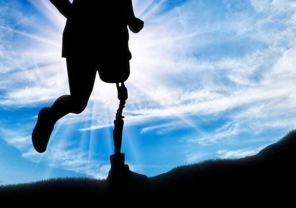 Человек с протезной ногой бежит вверх по холму
