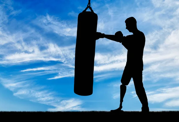 Silhouette of a disabled man with a leg prosthesis, training with a punching bag — Stock Photo, Image