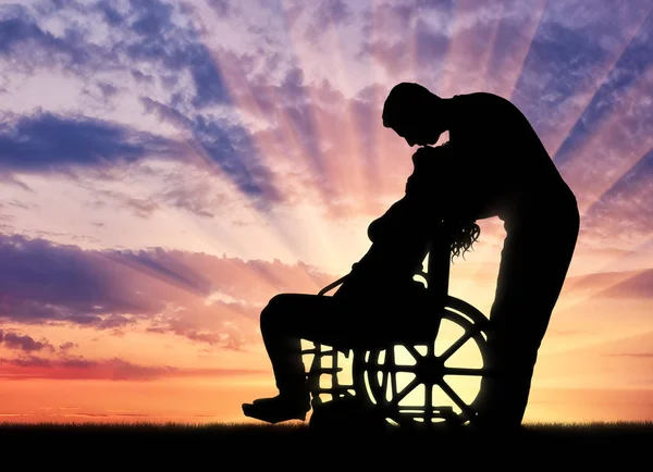 Silhouette of a man kissing a disabled woman in a wheelchair