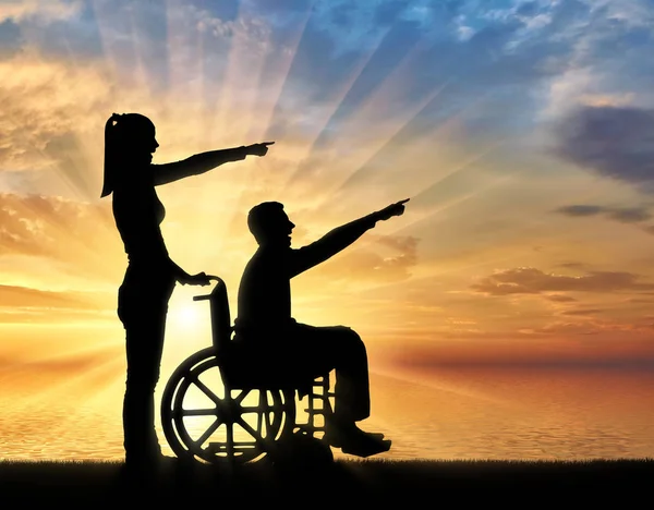 휠체어와 그의 아내에서 장애인된 남자의 실루엣 바다로 좋은 시간을가지고 — 스톡 사진