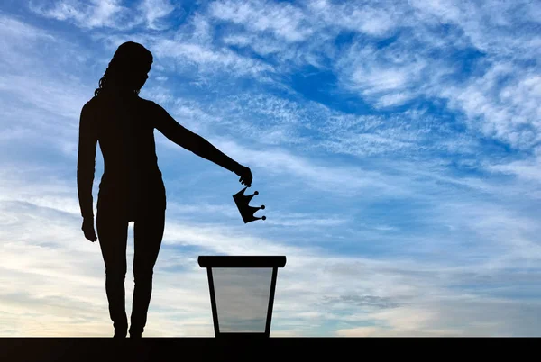 Silueta de una mujer tirando una corona en un cubo de basura —  Fotos de Stock