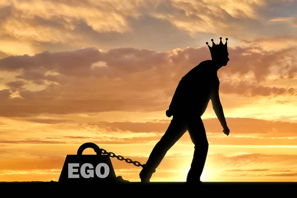 Een groot gewicht in de vorm van een ego is geketend aan de voet van een egoïstisch en narcistisch man met een kroon op zijn hoofd — Stockfoto