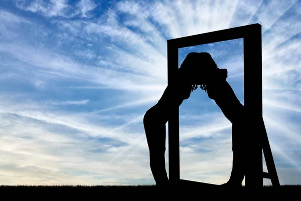 Silueta de una mujer narcisista abrazando su reflejo en un espejo — Foto de Stock