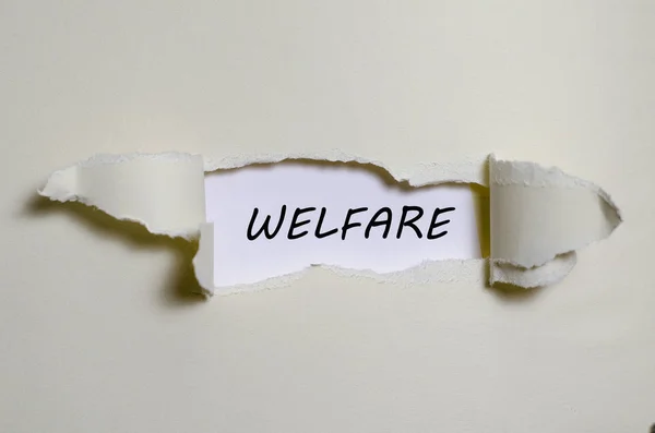 La parola welfare appare dietro la carta strappata — Foto Stock