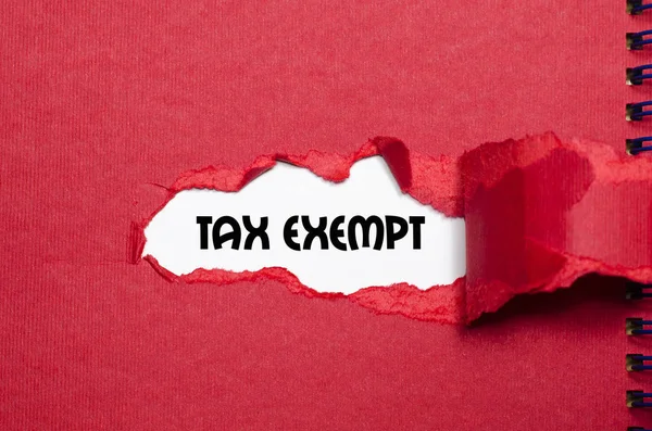 Le mot exonéré d'impôt apparaissant derrière le papier déchiré — Photo
