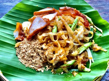 Pad Thai 'yi kapat, Tayland yemeği ünlü erişteli, kızarmış yumurta, domuz eti, uzun fasulye ve fıstık, muz yaprağı tabağı ve bambu tepsisi koy Tayland usulü restoranda, lezzetli tatlı baharatlı.