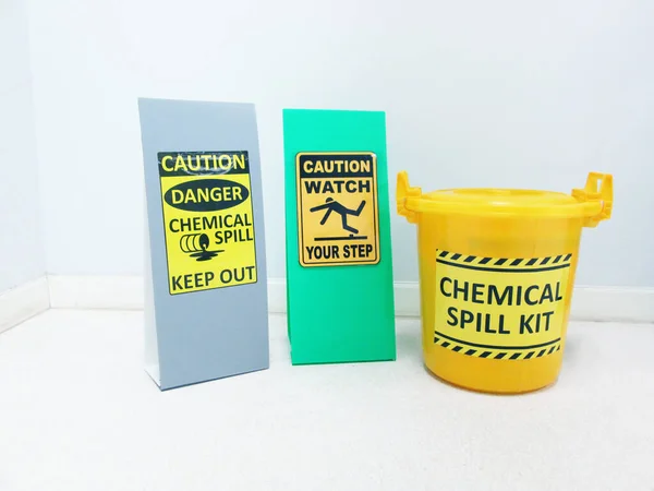 The Chemical Spill kit in yellow bucket and warning danger caution hazard tag sign or symbol for emergency response situation when the chemical spill out, safety first in laboratory workplace concept.