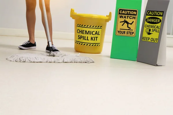 Janitor cleaning floor in medical service room or laboratory with caution tag sign watch your step and chemical spill out beside chemical spill kit yellow bucket for response chemical spill out cases.