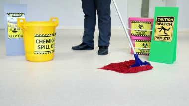 Temizlikçi erkek, tıbbi servis odasında ya da laboratuarda ikaz işaretli. Bastığınız yere dikkat edin. Biyolojik tehlike seti, kimyasal atık seti, kimyasal atık için sarı kova..