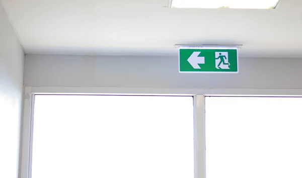 Fire Exit sign on the ceiling entry the fire escape, green safety light symbol isolated in white window. Caution for warning in dangerous fire situation, Risk assessment management safety workplace.