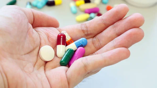 Woman hands holding a purple capsule of Clindamycin and multi-color capsules and drugs, used to treat bacterial infections, or treat patients who have an allergic reaction to penicillin. Isolated with colorful drugs, pills and tablet.