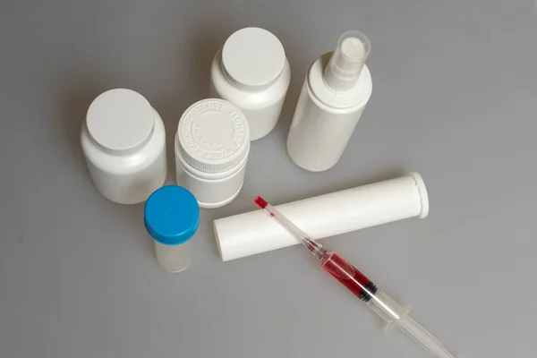 medical background. pill bottles, test tube, syringe with red liquid.