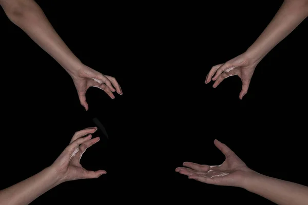 4 hands on a black background reaching for something in the center. The concept of ordering something, different things. earn a discount or item