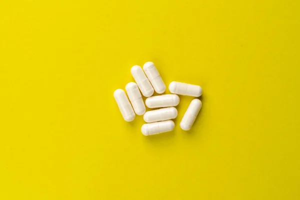 white pills on a yellow background. medical background