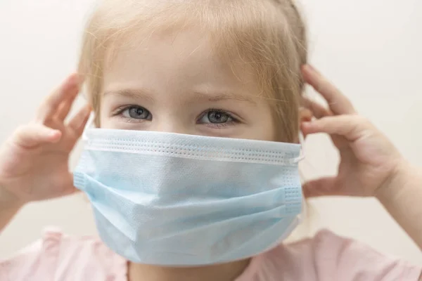 little girl in a disposable mask on a light background. Chinese virus epidemic protection