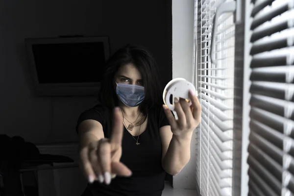 quarantine mask girl. a beautiful masked girl extended her hand forward with a raised finger. The sign does not come close, I\'m in quarantine in connection with the coronavirus.