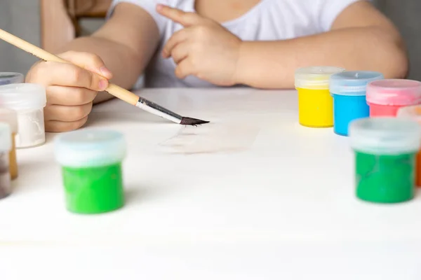 the girl leads with a brush on a white sheet of paper, will paint