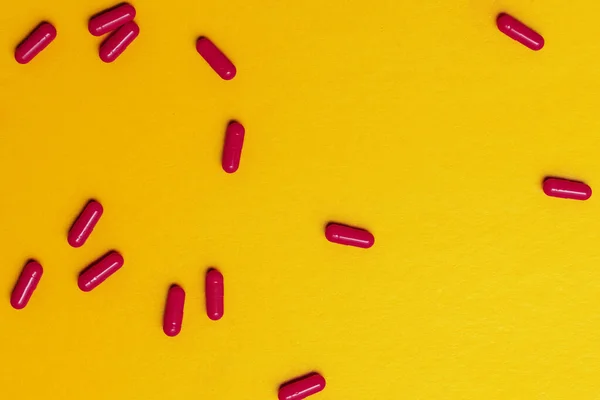 scattering of bright red pills on a yellow background.