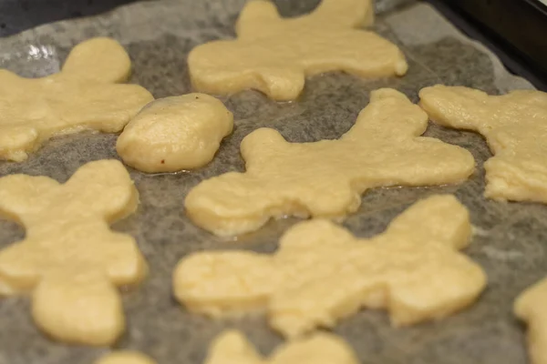 homemade cookies in the shape of men on a baking sheet before bakingculinary background