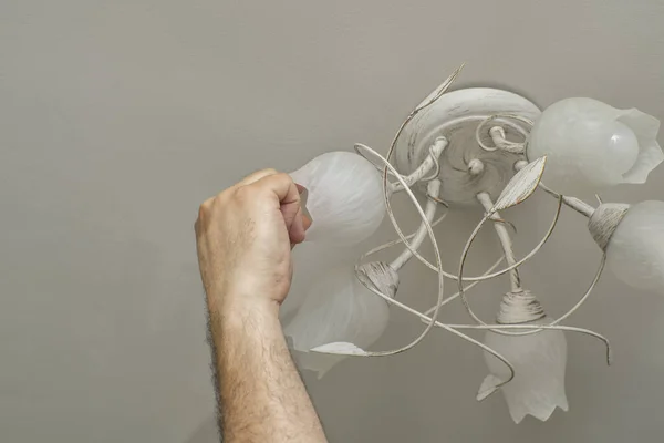 man changes a light bulb in a lighting device
