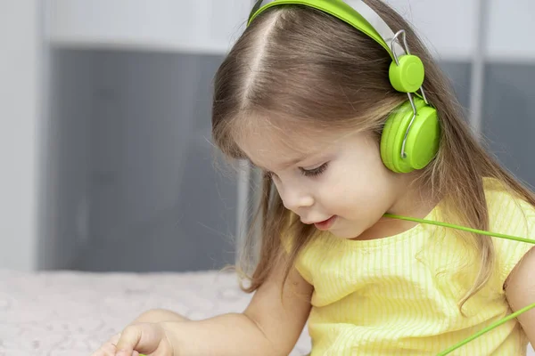 little girl with big green headphones listens to music,5g effect