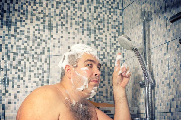 a large man in foam is standing in the bathroom and points to a hanging shower, water does not pour. shutdown of water in the water supply