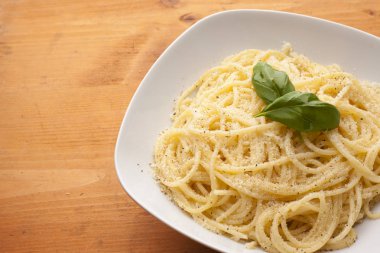 Spagetti bir plaka üzerinde ahşap te fesleğen ve parmesan peyniri ile