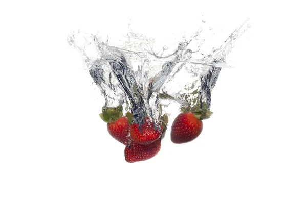 Fruits frais tombés dans l'eau avec éclaboussure sur fond blanc — Photo