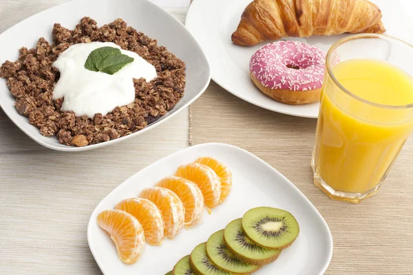 A healthy breakfast with croissants, muesli, yogurt, mint, juice