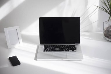 Beyaz arka plan ile beyaz masanın üstünde laptop