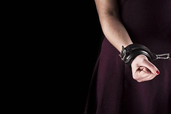 Submissive woman wearing a purple dress in leather handcuffs on — Stock Photo, Image