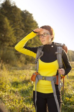Genç kadın sırt çantasında bir çayır yolu izler. Su hiking
