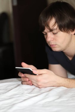 Karantinada evden çalışan bir adam, yatakta uzaktan çalışan bir adam.