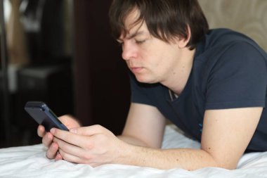 Karantinada evden çalışan bir adam, yatakta uzaktan çalışan bir adam.