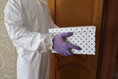 Eve teslim, koruyucu giysili, maske ve eldivenli bir adam grip salgınına bir kutu getirdi, koronavirüs salgını.