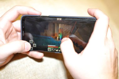 Moskova Rusya-Mart 2020: Elinde alet tutan bir çocuğun elleri, telefonda oynayan bir çocuğun elleri