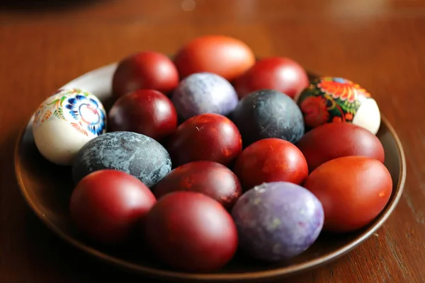 Easter painted eggs on a plate, purple, red, maroon, blue, black eggs, Easter traditions