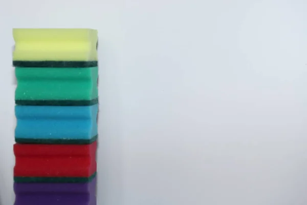 A espuma azul vermelha amarela verde da esponja para lavar pratos em um fundo branco usa como um fundo, há subtexto do lugar — Fotografia de Stock
