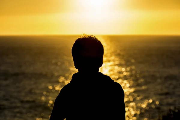 日没のティーンエイ ジャーの男の子のシルエット — ストック写真